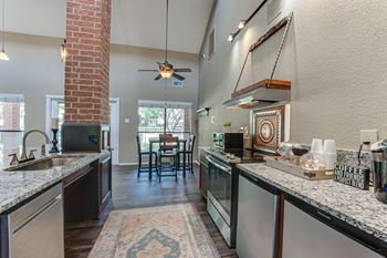 A kitchen with a brick column and a rug on the floor.